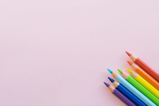 Color pencils on Pink paper background, copy space. Office supplies, back to school. Top view.