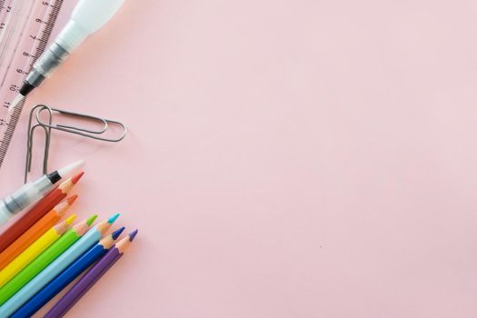 School drawing supplies on pink background. Free space for text. Back to school. Top view border of colour pencils, ruler and brushes