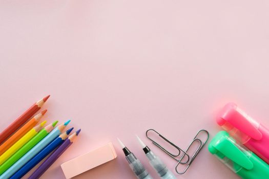 School and Office drawing supplies on pink background. Free space for text. Back to school. Top view border of colour pencils, marker and brushes