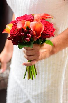 bride wearing a modern wedding bouquet of roses against a white wedding dress