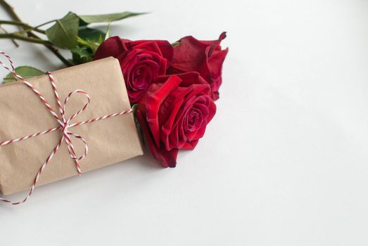 Composition of gift and bouquet of red roses on white background . Happy Valentines Day. Top view. Space for text. Copyspace