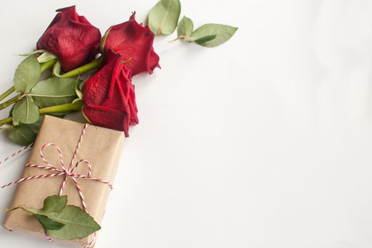 Composition with gift and bouquet of red roses on white background . Happy Valentines Day. Top view. Space for text. Copyspace