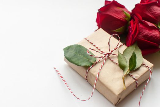 Composition of gift and bouquet of red roses on white background . Happy Valentines Day. Top view. Space for text. Copyspace