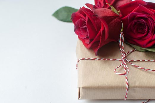 Composition of gift and bouquet of red roses on white background . Happy Valentines Day. Top view. Space for text. Copyspace