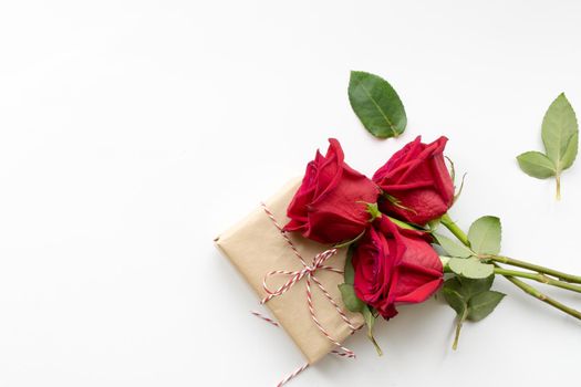 Composition of gift and bouquet of red roses on white background . Happy Valentines Day. Top view. Space for text. Copyspace