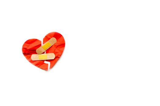 Broken red heart symbol with medical patch on white background, love concept. healing. Copyspace