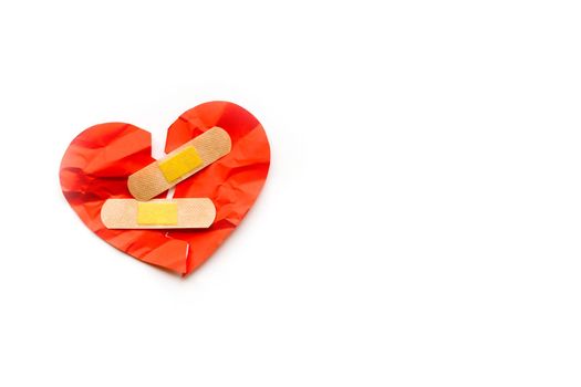 Broken red heart symbol with medical patch on white background, love concept. healing. Copyspace