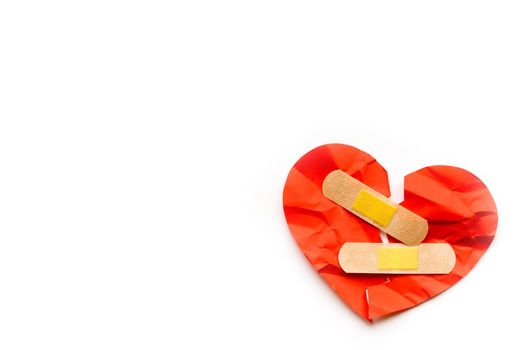 Broken red heart symbol with medical patch on white background, love concept. healing. Copyspace