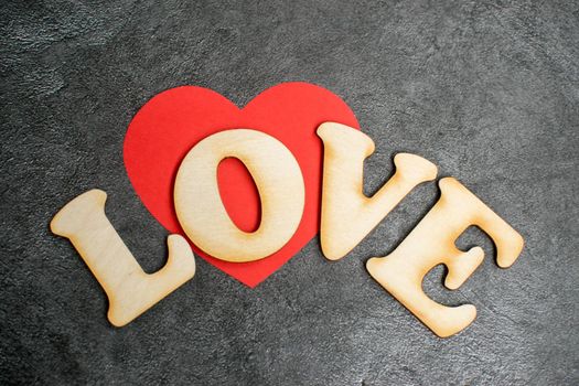 Valentines Day card background, red cute heart made of paper with decorative wooden word on dark background. Valentine Day romantic. Love concept.