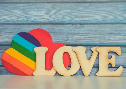 Valentines Day card background, Rainbow cute heart like a LGBT pride rainbow flag with red paper heart and decorative wooden word. Valentine Day romantic. Love human rights and freedom concept. Copyspace