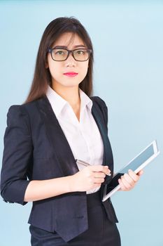 Young Asain women in suit standing using her digital tablet against blue background