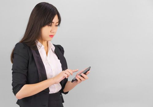 Young Asian women in suit standing posing using her phone against gray background