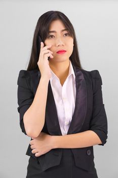 Young Asian women in suit standing posing using her phone against gray background