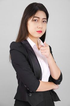 Asian woman in suit looking at camera and pointing finger on gray background