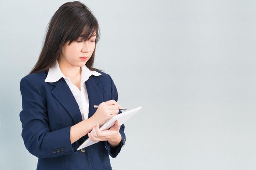 Asian woman in suit using computer digital tablet isolated on gray background