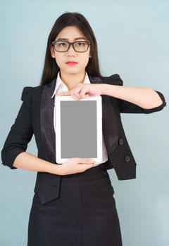 Young asian women in suit holding her digital tablet standing against green background