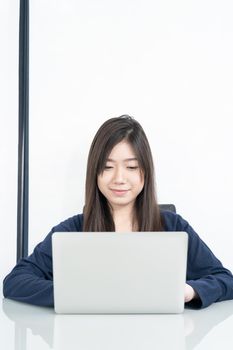 Young female student sitting in living room using laptop at desk learning online