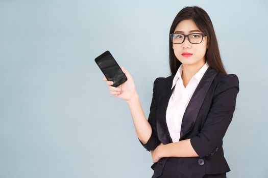 Young women in suit holding her smartphone standing against blue background