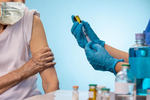 Closeup nurse doing vaccine injection to senior woman.