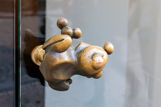 Stylish pen in the form of a frog on the glass door. The image of a frog in the form of a single handle glass door reflection.