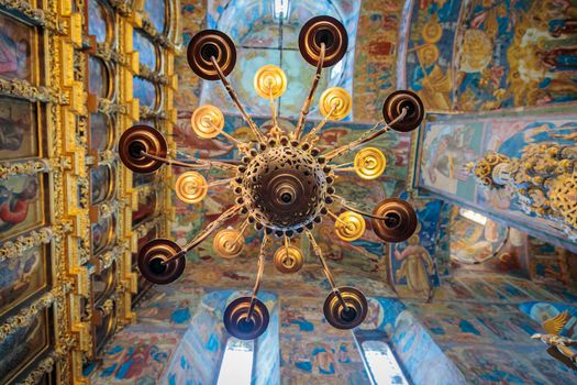 Church of Elijah the Prophet in Yaroslavl 11.07.2019. a high-hanging chandelier on the background of walls with painted icons of saints.