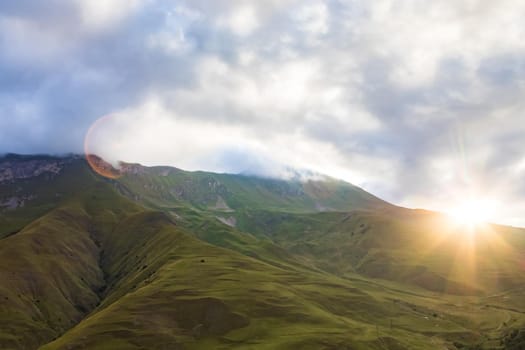 Early morning in the mountains, the first rays of the sun come out over the peaks of the ridge. Magnificent mesmerizing landscape.