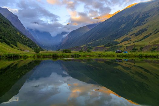 High mountains of the Caucasus with a beautiful view. Green vegetation and shrubs on sharp rocks, between the mountains of the lake. Magnificent mesmerizing landscape.