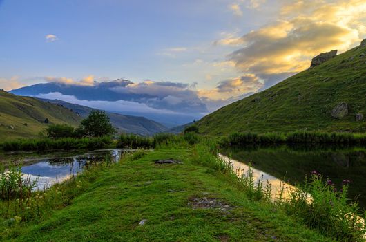 High mountains of the Caucasus with a beautiful view. Green vegetation and shrubs on sharp rocks, between the mountains of the lake. Magnificent mesmerizing landscape.