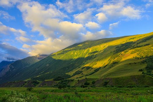 High mountains of the Caucasus with beautiful views. Green vegetation and dense forest above a blue sky. A great fascinating landscape.