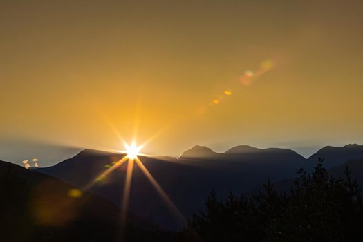 Early morning in the mountains, the first rays of the sun come out over the peaks of the ridge. Magnificent mesmerizing landscape.