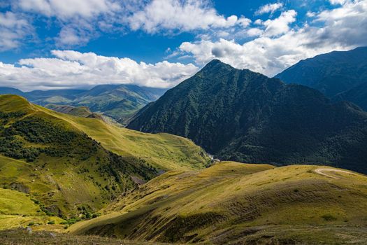 High mountains of the Caucasus with beautiful views. Green vegetation and dense forest above a blue sky. A great fascinating landscape.