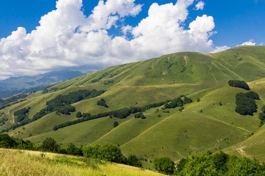 High mountains of the Caucasus with beautiful views. Green vegetation and dense forest above a blue sky. A great fascinating landscape.