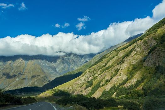Landscape of the green mountains of the Caucasus thick clouds cover the peaks of the ridge. The outgoing road to the valley.