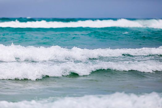 Powerful, stormy, foamy waves are picked up by the wind. White foam from bubbles of different sizes is scattered to the sides. Close-up.