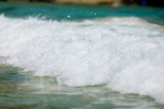 Powerful, stormy, foamy waves are picked up by the wind. White foam from bubbles of different sizes is scattered to the sides. Close-up.