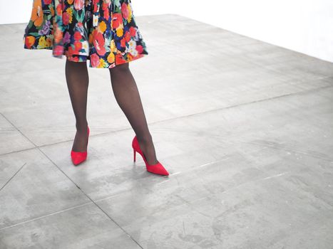 Woman legs wearing red high heels shoes on concrete floor close up view