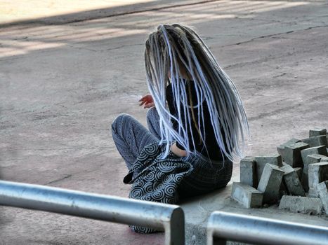 Long color gradient dreadlocks haired girl seated view from behind