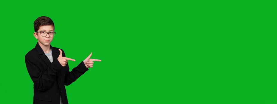 boy with glasses, pointing his hands to empty place isolated on green background. banner copy space. wide panorama picture.