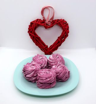 On a turquoise saucer, raspberry marshmallows for dessert with a heart for Valentine's Day.