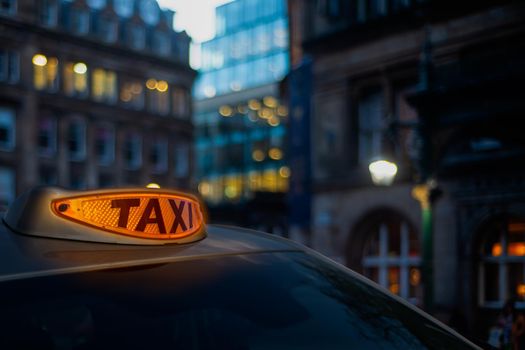 A Glowing Orange Taxi Light In A London Street At Twilight