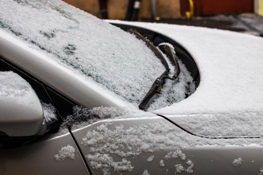 Snow on car, windshield wipers with snow close up.