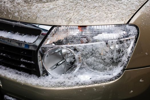 Car headlights covered with snow close up.