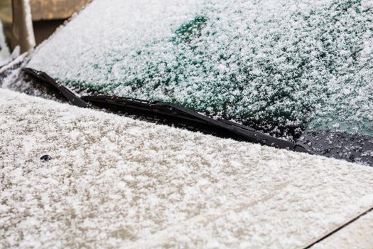 Snow on car, windshield wipers with snow close up.