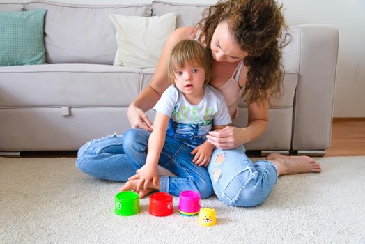 Mother and her son with Down syndrome playing with toys in their flat