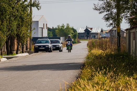 Rider on his enduro motorbike on a village road near Targoviste, Romania, 2020