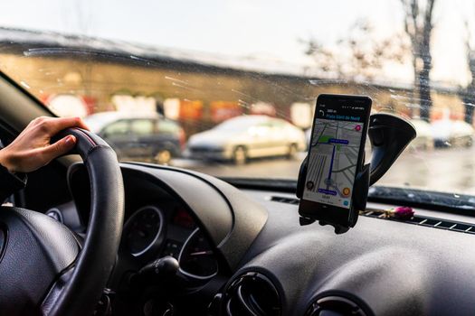 Using waze maps application on smartphone in car dashboard. Driver using maps app for showing the right route through the traffic in Bucharest, Romania, 2021