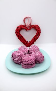 On a turquoise saucer, raspberry marshmallows for dessert with a heart for Valentine's Day.