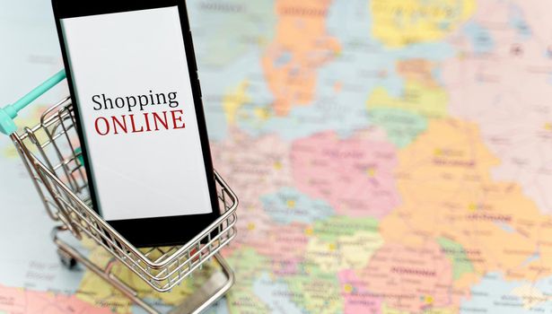 Mobile phone in shopping trolley. Online shopping concept.