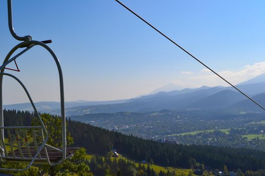 Summer lifts on a mountainside with mountains in the background