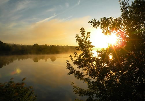 The first rays of the rising sun pass through the fog